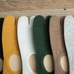 Close-up of assorted two-toe Tabi socks in various colors on a rustic wooden background