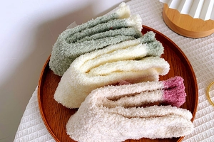 Detail of colorful coral fleece socks in green and pink on a wooden tray