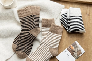 Détail de chaussettes en laine rayées marron et blanc sur une couverture douillette