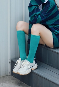 Detalle de calcetines altos color cian combinados con zapatillas blancas de suela gruesa