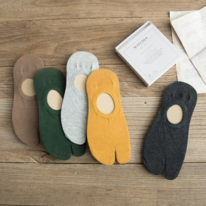 Close-up of assorted cotton tabi socks in five neutral tones on a vintage wooden desk