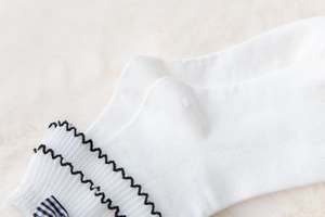 Detail of white cotton lolita socks with frilly lace edges and checkered bow decoration