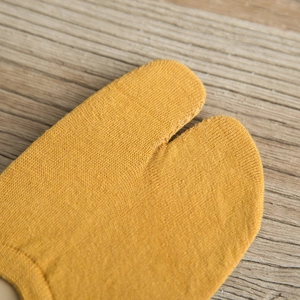 Close-up of ginger yellow split-toe cotton socks showing fine stitching and knit texture