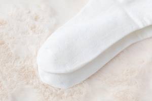 Macro shot of white knitted socks with soft bow detail on fuzzy background