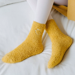 Close-up of ginger coral fleece warm socks with white smiley face embroidery on fabric