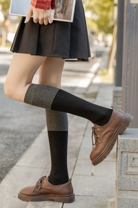 Détail de chaussettes montantes bicolores noir et gris avec chaussures en cuir marron