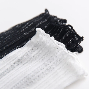 Detail of ruffle cuffs and breathable mesh texture on white and black knit socks