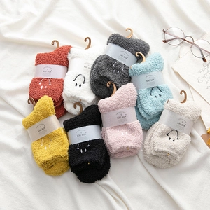 Close-up of colorful coral fleece socks set with embroidered smiley face on white fabric