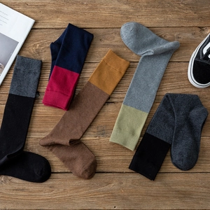 Détail de cinq paires de chaussettes hautes bicolores sur un fond en bois rustique