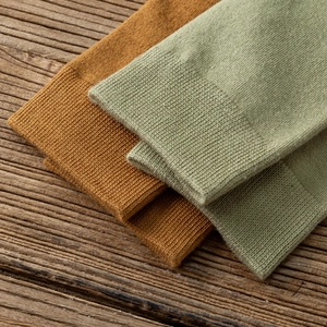 Détail de chaussettes hautes en tricot couleur gingembre et vert sauge avec bords côtelés