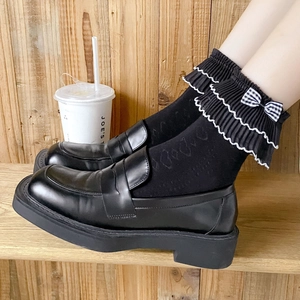 Japanese style frilly socks with plaid bow and black leather platform loafers on wood floor