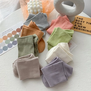 Flat lay of colorful cotton crew socks in eight Morandi shades on a textured surface