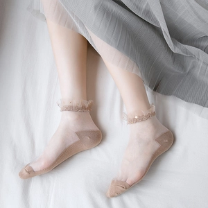 Detail of sheer mesh socks with ruffled cuffs and golden star accents in light coffee