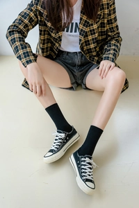 Detail view of cotton split-toe mid-calf socks paired with classic low-top canvas sneakers