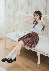 Detail of white cotton lace trim socks styled with black Mary Jane shoes and plaid skirt