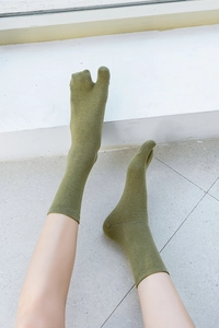 Olive green split-toe crew socks with fine knit texture shown on model in minimal setting