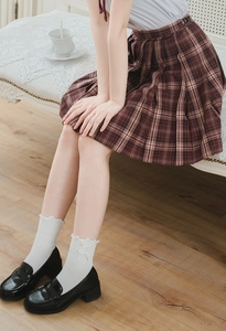 Detail of white ruffle trim socks with bows paired with a red plaid pleated skirt