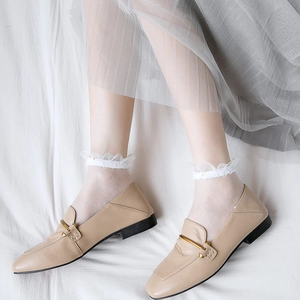 Beige pointed-toe loafers with gold metal detail worn with white lace socks