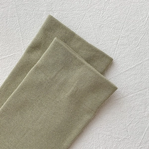 Detail of olive green cotton sock featuring fine rib-knit texture and elastic cuff