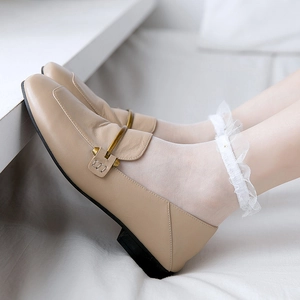 Close-up of beige square-toe leather loafers with gold buckles and lace socks
