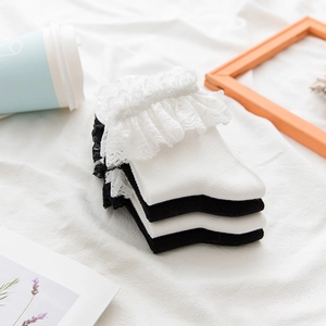 Close-up of black and white Lolita socks with wide mesh lace trim on soft fabric