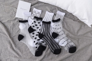Dettaglio di calze in mesh trasparente con pois, motivi a cuore e strisce verticali sottili