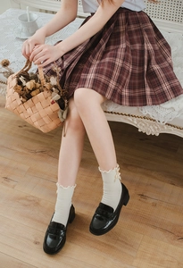 Close-up of cream ruffled socks with bows and brown plaid pleated skirt for JK uniform
