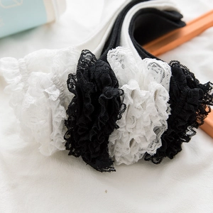 Close-up of intricate white and black floral lace trim on soft Lolita style mid-calf socks