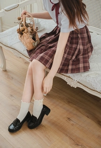 Detail of white Lolita socks with double bows and red plaid JK skirt on vintage bench