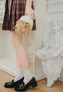 Detail of ruffle trim socks with bows paired with loafers and a plaid pleated skirt