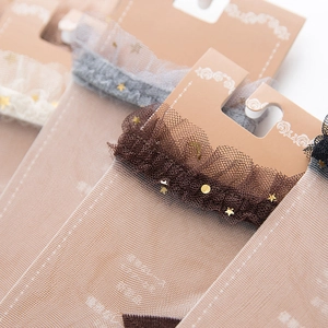 Detail of sheer mesh socks featuring lace trim and gold star moon foil prints