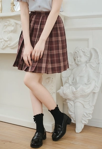 Detail of brown plaid pleated skirt with JK style socks and black loafers shoes