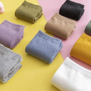 Flat lay of colorful split-toe socks in purple, blue, and yellow on a dual-tone background