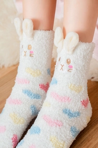 Detail of plush white coral fleece socks featuring 3D bunny ears and heart embroidery