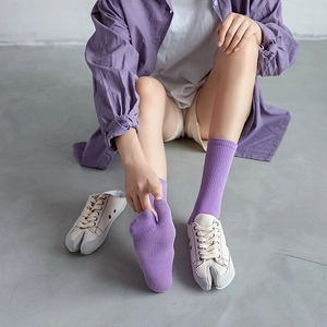 Primo piano di calzini tabi viola e scarpe da ginnastica in tela con punta divisa