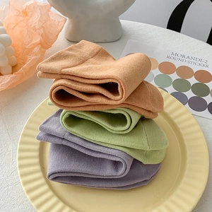 Three pairs of Morandi colored cotton socks stacked on a decorative plate