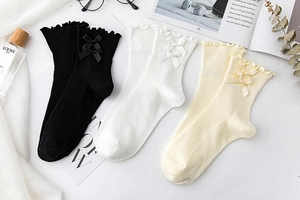 Detail of three pairs of ribbed cotton mid-calf socks with bows and ruffled edges