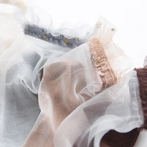 Macro shot of sheer mesh socks with wavy lace edges and golden star sequin detailing