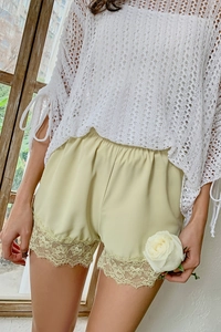 Detail of light green silk safety shorts with delicate lace trim and ribbon bow accent