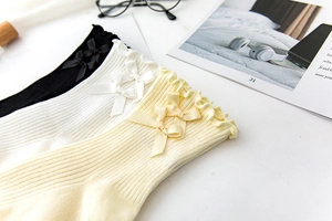 Detailed view of ribbed cotton socks with ruffle edges and satin bows in three colors