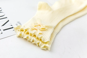 Macro detail of ribbed yellow socks with ruffled edges and silk ribbon bows