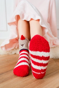 Close-up of fluffy red and white striped coral fleece socks with cute 3D bear detail