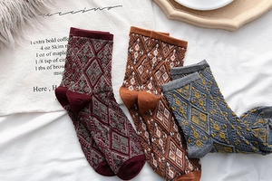 Detail of three retro argyle knit socks in burgundy, caramel and grey colors