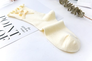 Detail of cream lolita mid-calf socks with frilled edges and delicate double bows