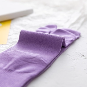 Dettaglio ravvicinato di calze tabi viola in maglia fine con design a punta divisa
