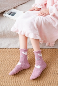 Detail view of pink coral fleece socks featuring white heart patterns and wavy edges