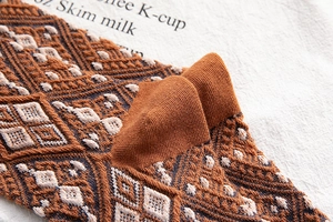 Close-up of retro knit mid-calf socks with caramel geometric argyle pattern texture
