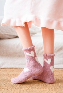 Detail of pink coral fleece socks with white heart patterns and elegant ruffled cuffs