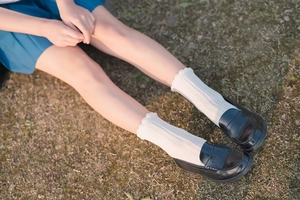 White lace trim crew socks styled with black loafers on soft outdoor grass scenery