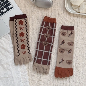 Detailed view of three cute Japanese-style five-finger socks with bear and flower patterns